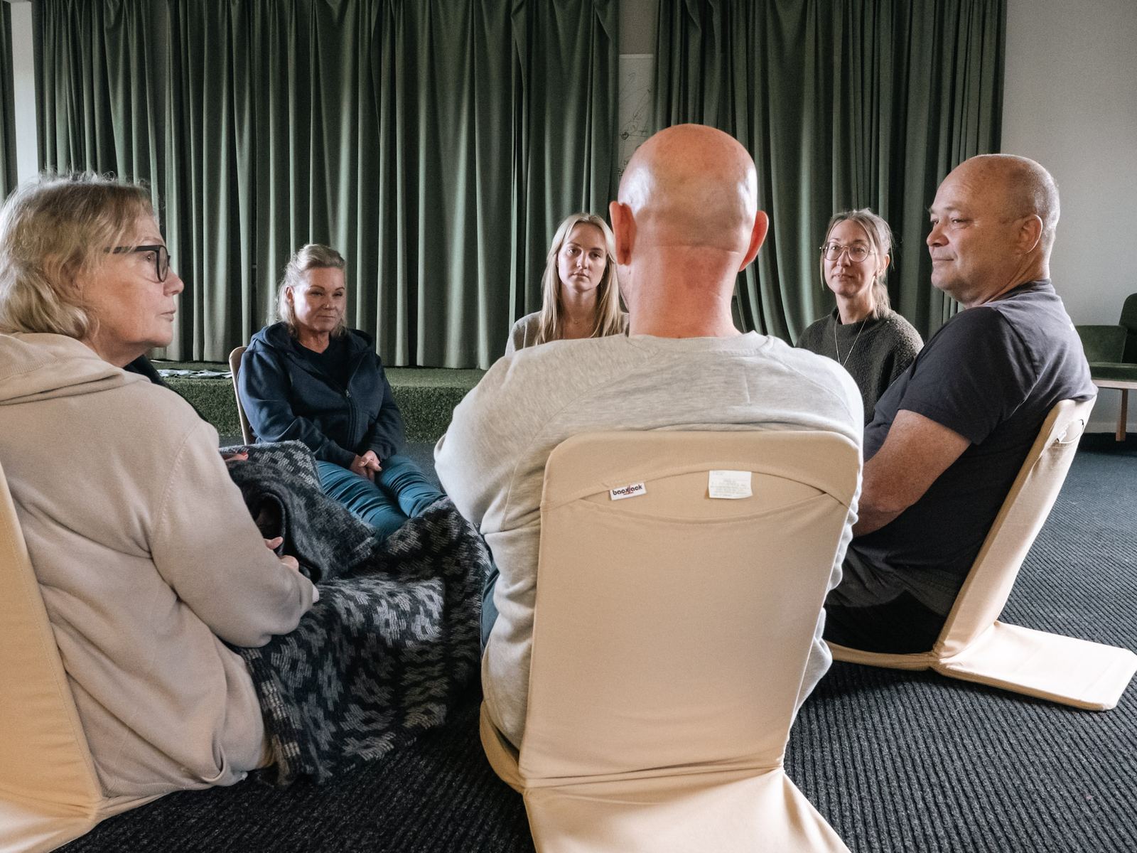 Participants sitting on floor chairs in the room, facing each other.