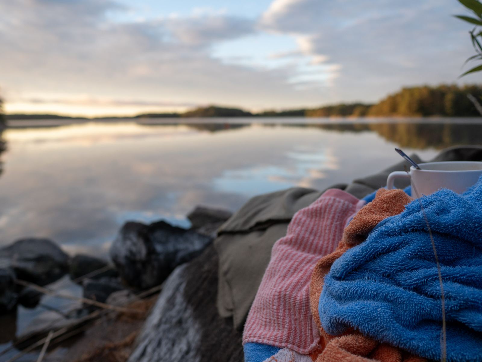 Handdukar på stenarna vid sjön i gryningen.