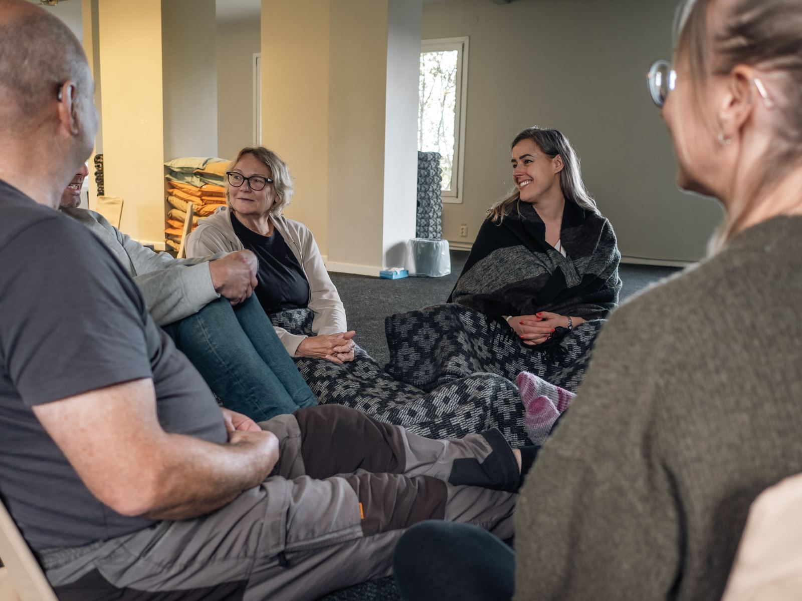 Participants sitting on the floor of the course room, talking; one of them is laughing.