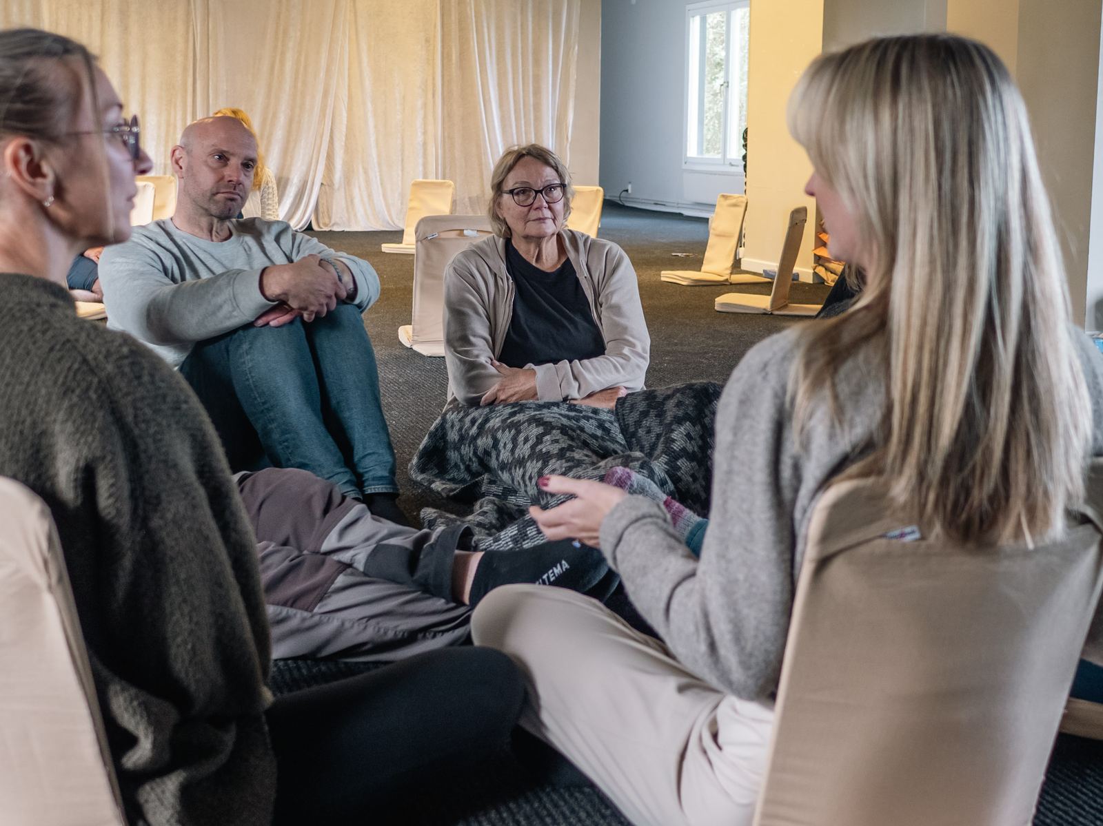 Deltagare sitter nära varandra på golvet i kursrummet och lyssnar.