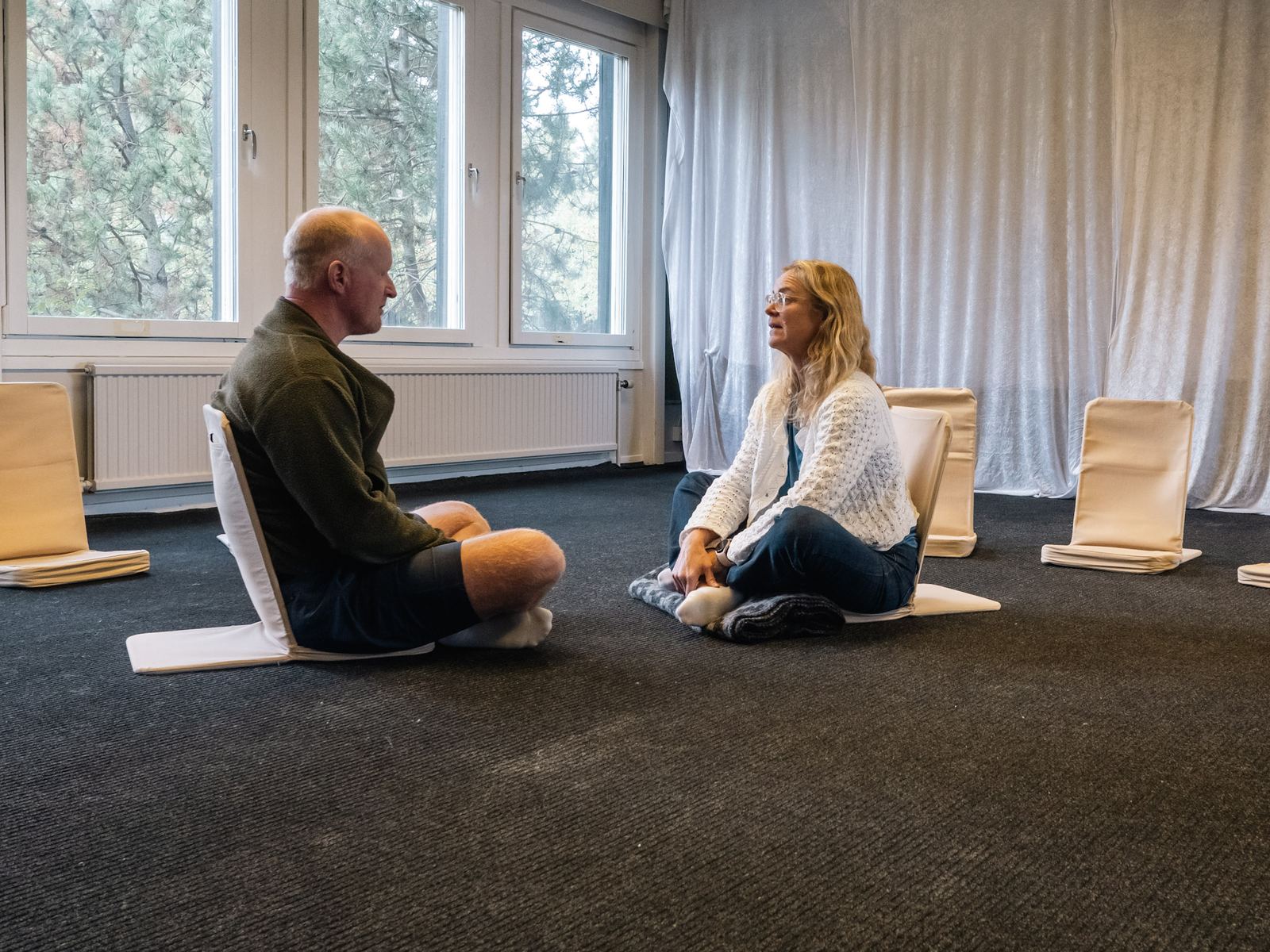 Two participants sitting on the floor facing each other, talking.